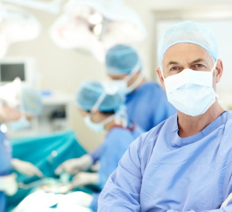 Portrait of a senior surgeon wearing a face mask and hospital scrubs in an operating theatre - Copyspace